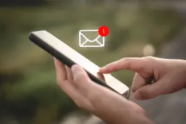 uma mão segurando um celular e um ícone de mensagem em destaque.